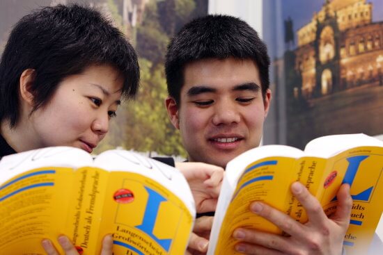 Deutsch im Ausland mit Bild von Menschen mit deutschem Wörterbuch in der Hand